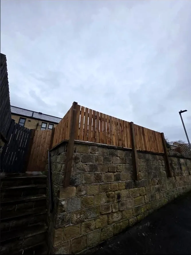 Completed timber boundary fencing installed above a stone wall