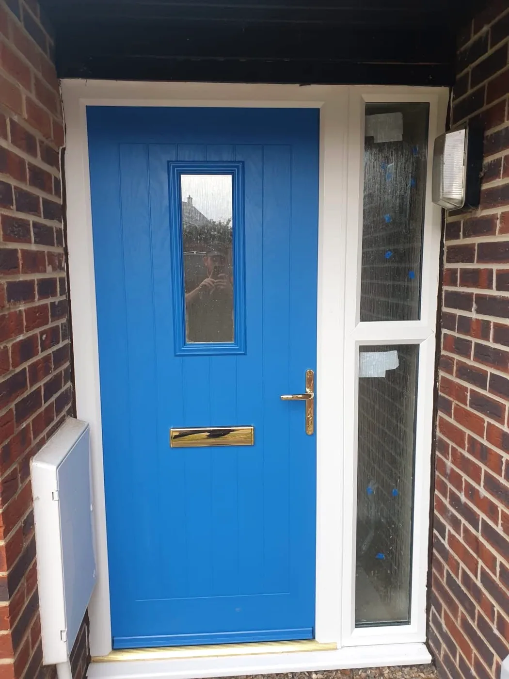 Blue entrance door with narrow glazed panel and white side glazing